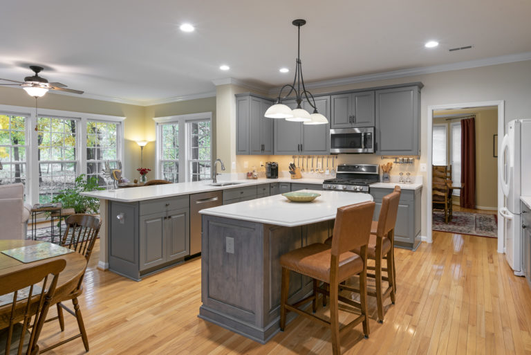 A gray kitchen with solid white quartz countertops and stainless-steel appliances.