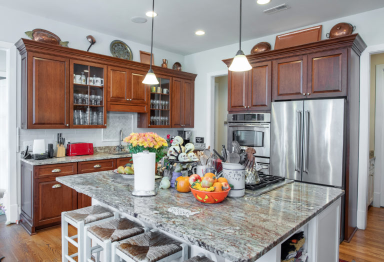 The gray-tan granite countertops compliment the cherry kitchen cabinets and contrasting white island.  