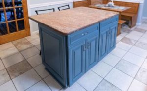 Blue kitchen cabinets complementing a light-colored countertop and light flooring