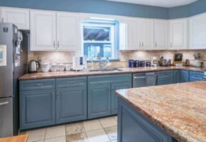 A bright, lively kitchen with blue and white cabinetry and light-colored countertops