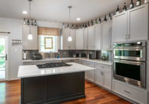 Beautifully remodeled kitchen with light gray cabinets and a dark gray MDF kitchen island