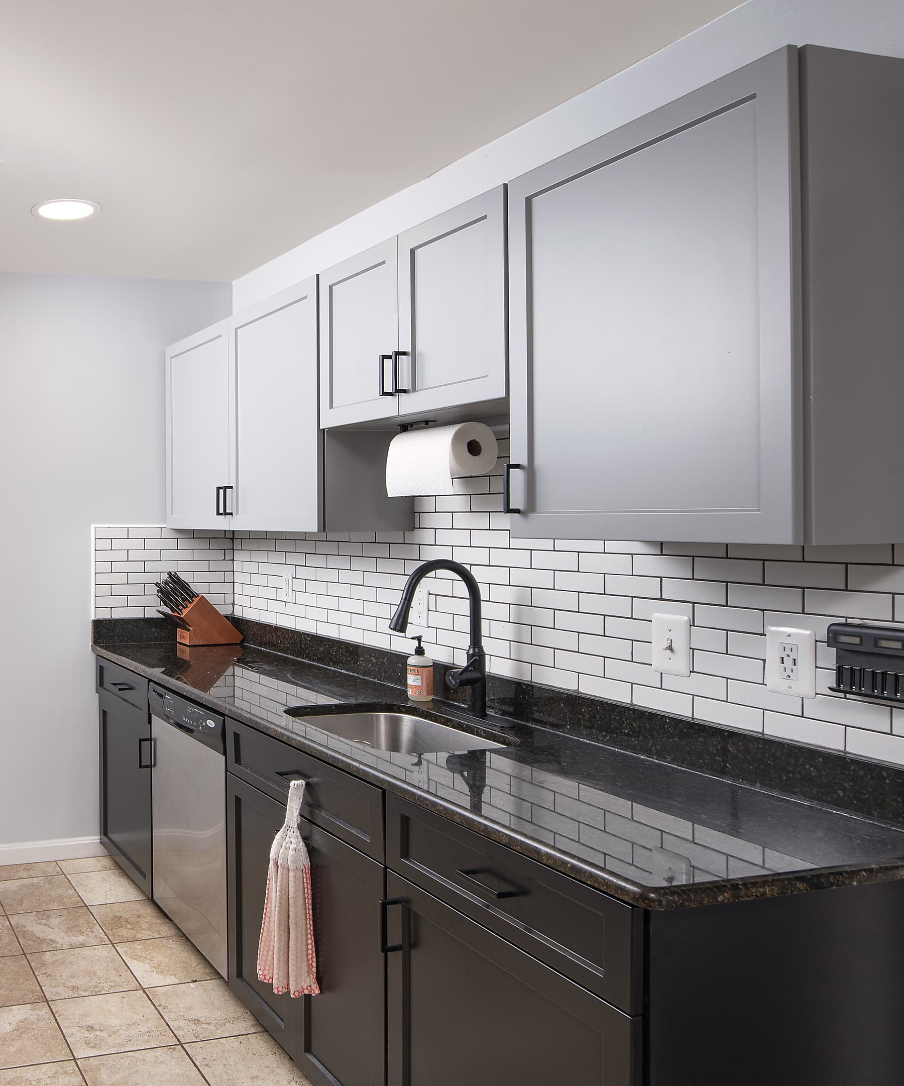 Fog gray wall cabinets and black base cabinets emphasize the existing white subway tile backsplash.