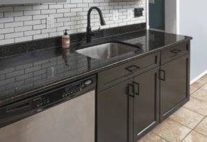 Stunning black kitchen cabinets matching a dark-colored countertop 