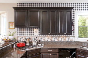 Dark cabinetry complemented by natural-colored counters and a patterned backsplash