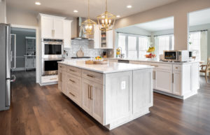 Recessed paneled MDF cabinet doors in bright white with a contrasting gray-brown island and shaker style molding.