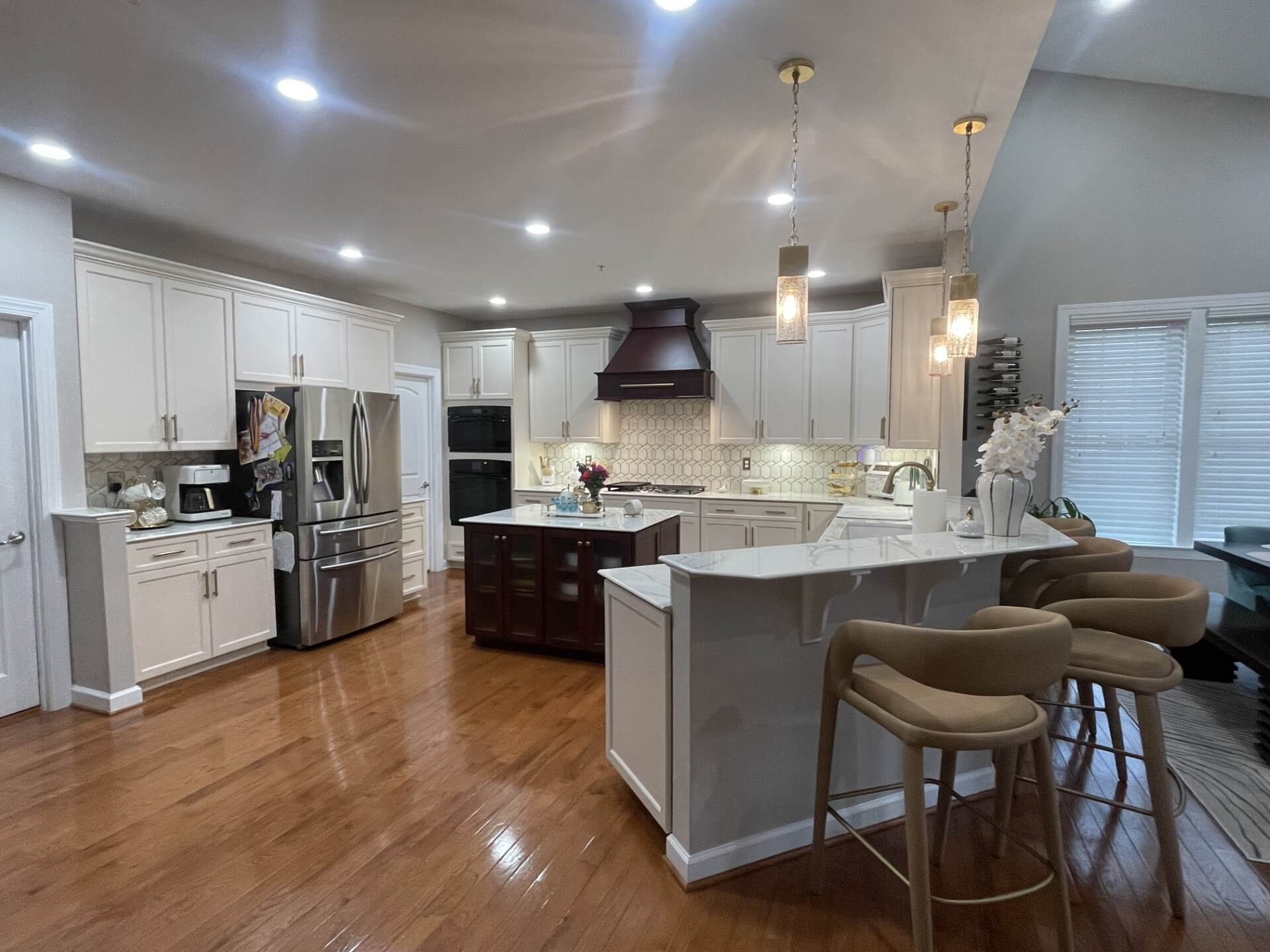 Kitchen with white cabinets and silver hardware, a dark brown kitchen island and light brown flooring