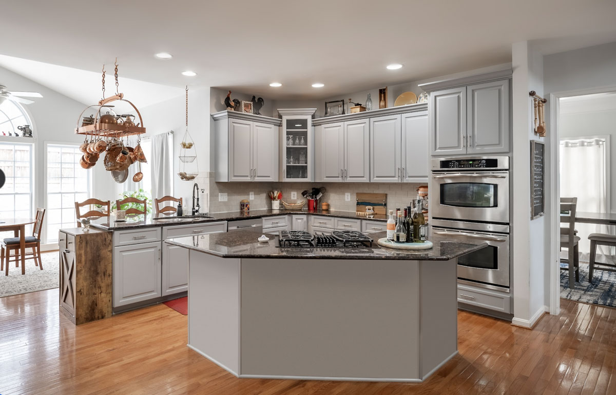 Kitchen with gray raised paneled cabinets wood floors