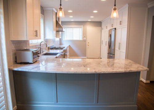 This kitchen had a big transition! Walls, soffits, laminate countertops and the old tile backsplash were all torn out and a doorway was widened to make room for the ‘new’ improved kitchen. Granite countertops were installed and an 18 gauge stainless steel apron sink was added. Functional as well as striking, the large undermount sink has a built in soap dispenser, water filter and insta-hot faucet. New cabinets were added and both new and existing cabinets were refaced in white with new Amesbury doors and drawer fronts added. Indie the cabinets, full extension rollouts and a lazy susan were added to upgrade the storage capabilities.