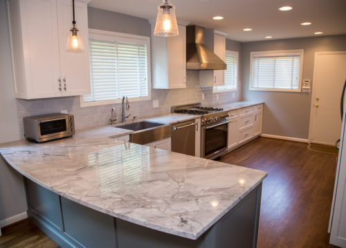 This kitchen had a big transition! Walls, soffits, laminate countertops and the old tile backsplash were all torn out and a doorway was widened to make room for the ‘new’ improved kitchen. Granite countertops were installed and an 18 gauge stainless steel apron sink was added. Functional as well as striking, the large undermount sink has a built in soap dispenser, water filter and insta-hot faucet. New cabinets were added and both new and existing cabinets were refaced in white with new Amesbury doors and drawer fronts added. Indie the cabinets, full extension rollouts and a lazy susan were added to upgrade the storage capabilities.