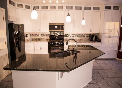 By repairing structural damage and keeping their existing cabinet boxes, these homeowners saved a bunch refacing their kitchen with Kitchen Saver. The door style is LaFayette, and the finish is designer white colourtone on MDF. Those savings translated into custom features like cabinet extensions, new cabinets, rollouts, pullout trash and recycling bins, and contrasting granites on their countertop and island. Beautiful!