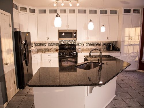 By repairing structural damage and keeping their existing cabinet boxes, these homeowners saved a bunch refacing their kitchen with Kitchen Saver. The door style is LaFayette, and the finish is designer white colourtone on MDF. Those savings translated into custom features like cabinet extensions, new cabinets, rollouts, pullout trash and recycling bins, and contrasting granites on their countertop and island. Beautiful!