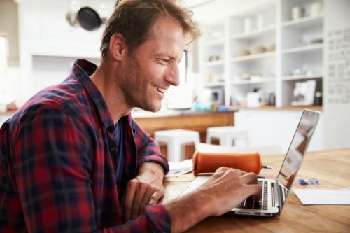 Man working on laptop in kitchen